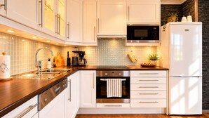 A modern kitchen with white cabinetry, stainless steel appliances, and a wooden countertop.