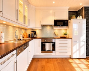 Una cucina moderna con mobili bianchi, elettrodomestici in acciaio inossidabile e un piano di lavoro in legno.