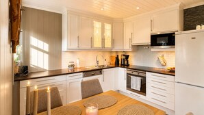 A modern kitchen with white cabinets, a wooden dining table with placemats, and a built-in oven.