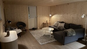 Una habitación acogedora con un sofá, una mesita, una lámpara y una silla.