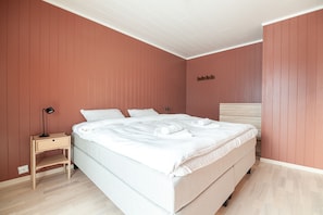 A bedroom with a bed, a nightstand, and a wall-mounted shelf.