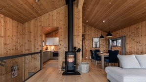 A wooden interior with a fireplace, a dining area, and a sofa. - Moderne leilighet i Vestlia . Ski in ski out (Hol)