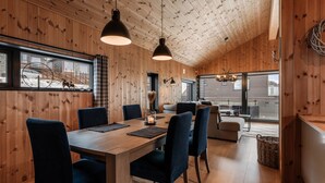 A wooden interior with a dining table, chairs, pendant lights, and a view of the outside. - Moderne leilighet i Vestlia . Ski in ski out (Hol)