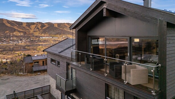 A modern two-story building with large windows, a balcony, and a view of a valley and mountains. - Moderne leilighet i Vestlia . Ski in ski out (Hol)