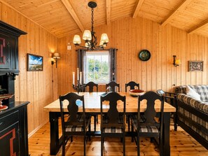 Ein Holzinterieur mit Esstisch, Stühlen, einer Couch und einer Pendelleuchte.