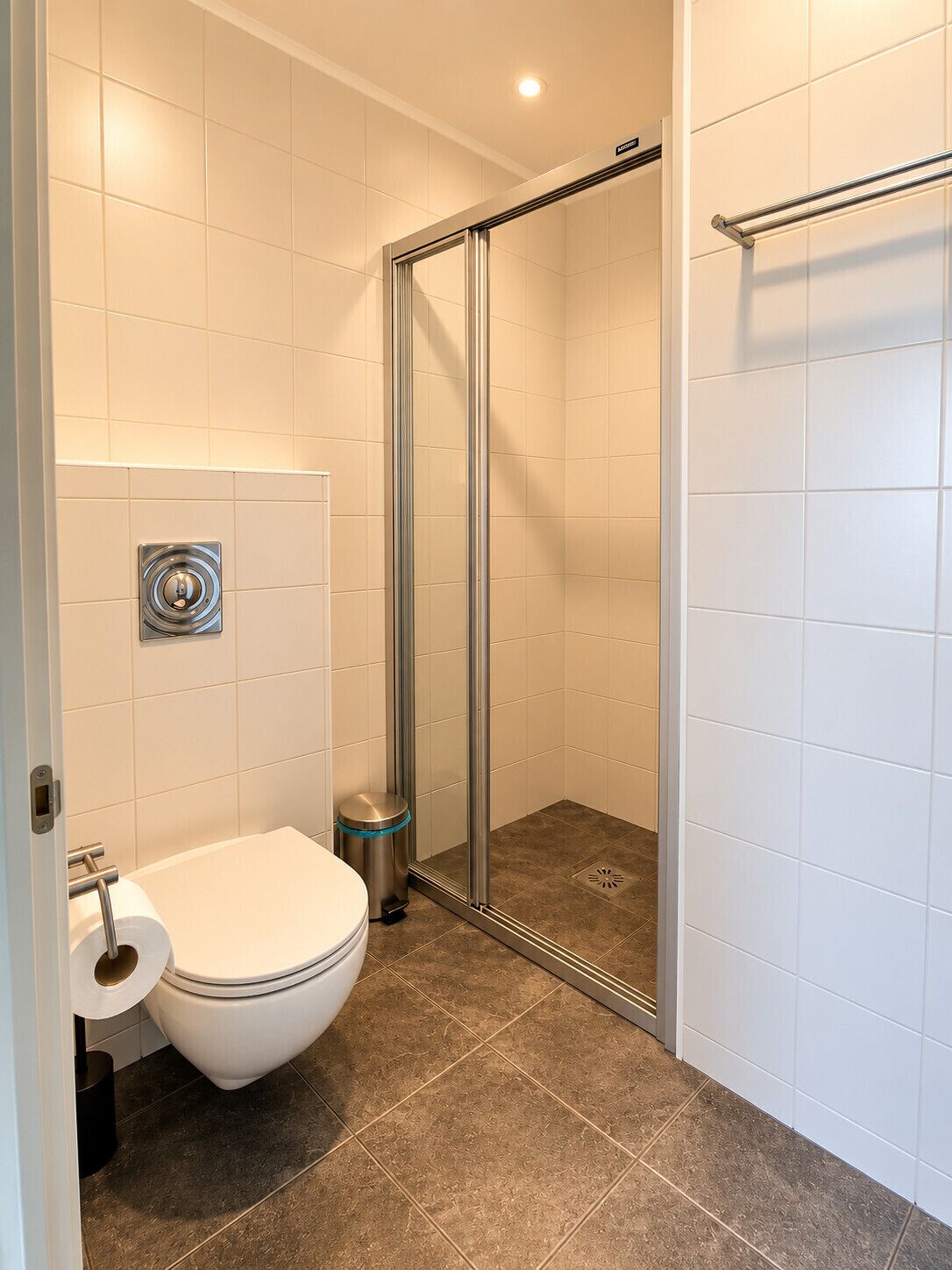 A bathroom with a toilet, a shower with a glass door, and a towel rack.