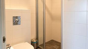 A bathroom with a toilet, a shower with a glass door, and a towel rack.