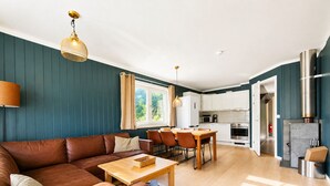 A modern living room with a brown leather sofa, a wooden coffee table, and a dining area with a wooden table and chairs.