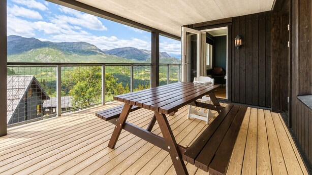 A wooden deck with a picnic table, a view of mountains, and a dark wooden wall. - Ski in/Ski out with Sauna and Modern Mountain Comfort (Hemsedal)