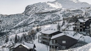 A mountain lodge with multiple buildings, a ski slope, and a snow-covered forest. - Ski in/Ski out with Sauna and Modern Mountain Comfort (Hemsedal)