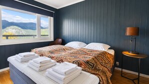 A bedroom with a bed, a window with a view, a bedside table, and a lamp. - Ski in/Ski out with Sauna and Modern Mountain Comfort (Hemsedal)