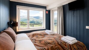 A hotel room with a large bed, a view of mountains, a flat-screen TV, and a fire alarm. - Ski in/Ski out and Perfect for Families (Hemsedal)