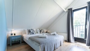 Une chambre à coucher avec un lit, une table de chevet, une fenêtre avec des rideaux et une vue sur l’extérieur.