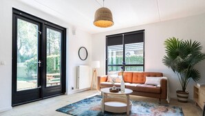 Un salon avec un canapé, une table basse, une lampe, une grande fenêtre et une plante en pot.