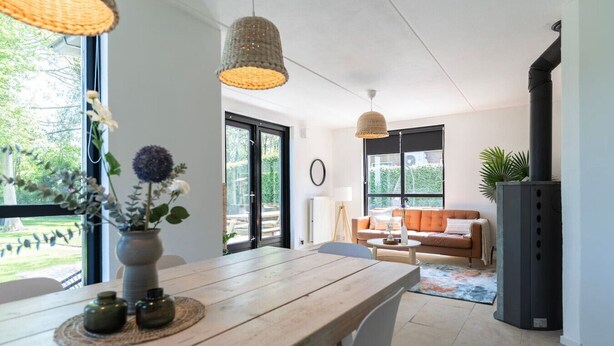 Un salon moderne avec une table en bois, un canapé et une cheminée noire.
