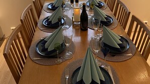 Une table à manger dressée pour six personnes, avec des sets de table, des verres et une bougie.