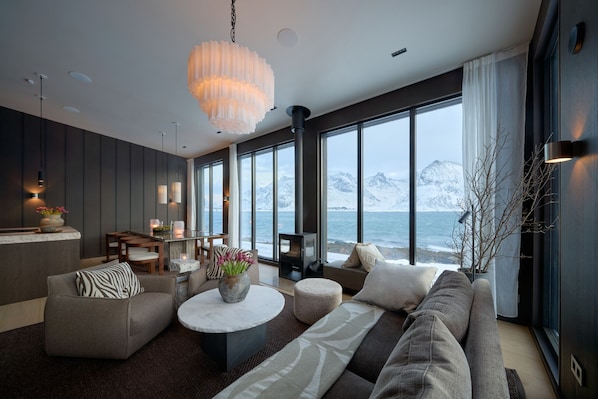 A modern living room with a large sofa, a coffee table, and a view of the ocean.