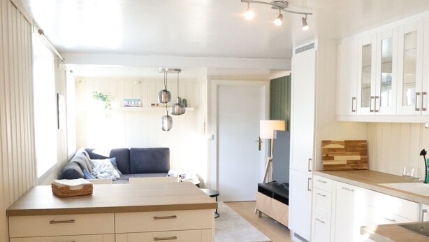 A modern kitchen with white cabinetry, a wooden countertop, and a built-in oven. - Central apartment in Lillehammer (Lillehammer)