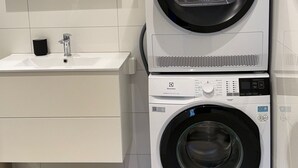 A modern bathroom with a double washing machine, a sink, and a mirror. - Central apartment in Lillehammer (Lillehammer)