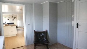 A room with a chair, a door, and a view into another room with a kitchen area. - Central apartment in Lillehammer (Lillehammer)