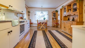 A kitchen with wooden cabinets, a dining table with chairs, and a patterned rug.