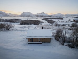 Een besneeerd landschap met een huis, een schuin dak en een klein voortertje.