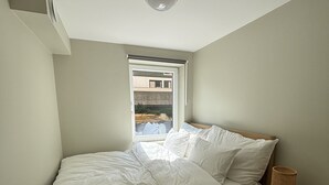 Ett sovrum med en säng, ett sängbord, ett fönster och en taklampa.
