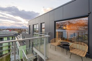 Ein modernes Gebäude mit Balkon, Glasgeländern und Korbstühlen.