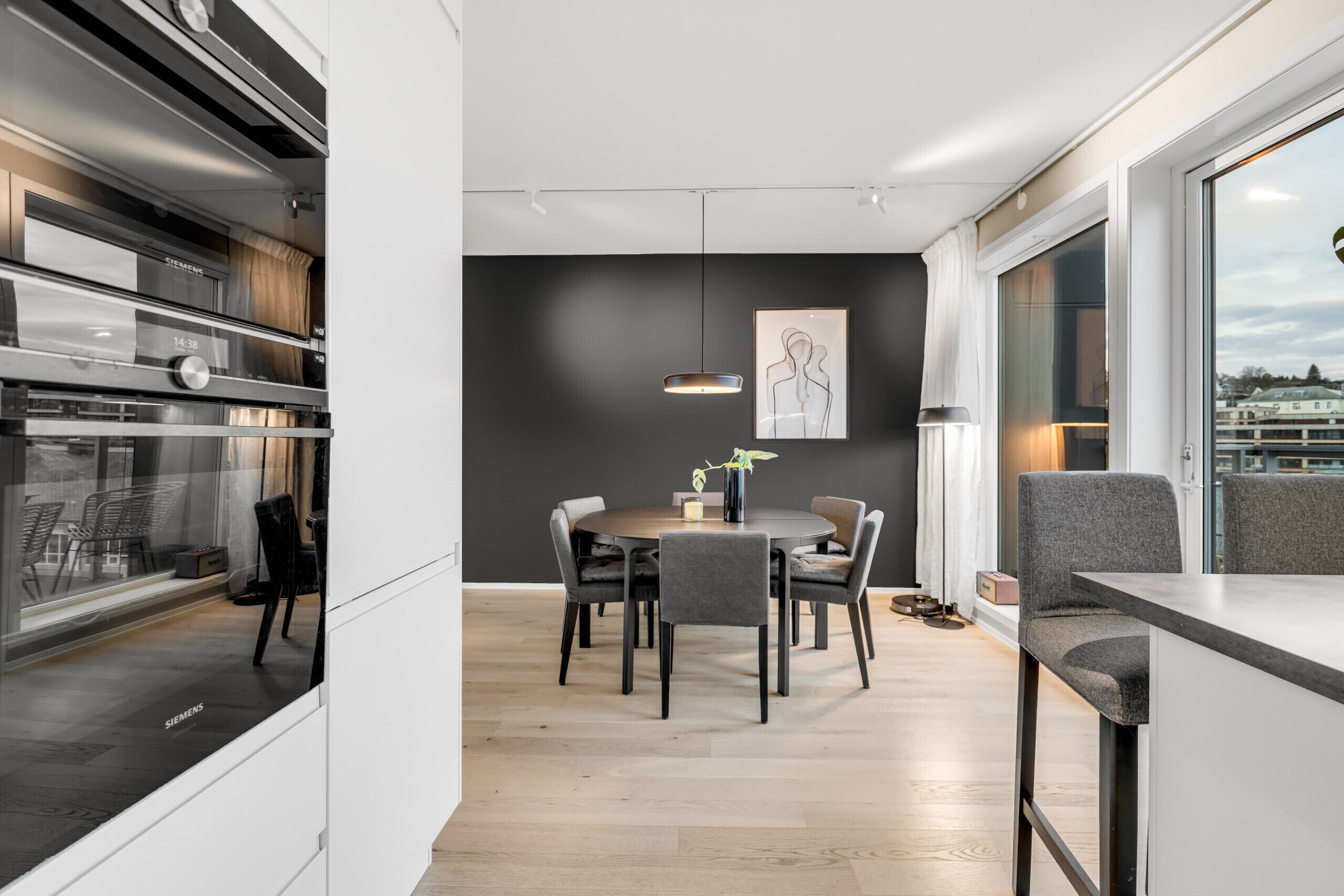 Una cocina moderna con horno integrado, un comedor con una mesa redonda y sillas, y un amplio ventanal con vistas.