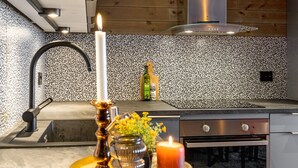 A modern kitchen with a wooden ceiling, a stainless steel range hood, and a black faucet. - Modern apartment in Golsfjellet (Gol)