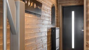 A hallway with wooden paneling, a refrigerator, a small appliance, and a door with a light. - Modern apartment in Golsfjellet (Gol)