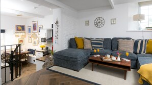 Ein modernes Wohnzimmer mit Sofa, Hocker, Couchtisch und Essbereich.