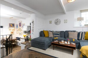 Un salon moderne comprenant un canapé, un pouf, une table basse et un coin repas.