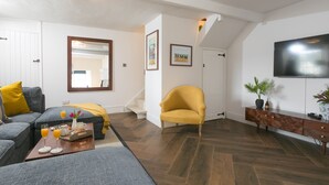 Ein Wohnzimmer mit einer Couch, einem Sessel, einem Couchtisch und einem Flachbildfernseher.