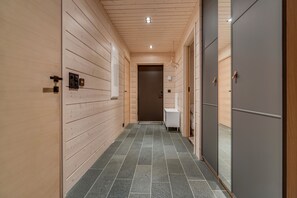 Ein Korridor mit Holzwänden und Fliesenboden, der zu einer Tür führt.