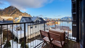 A balcony with a view of a lake, mountains, and buildings. - Aurora View Apartment Svolvær (Vågan)