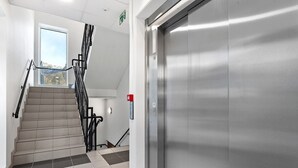 A modern elevator, a staircase with a handrail, and a fire alarm box. - Aurora View Apartment Svolvær (Vågan)