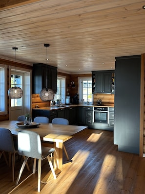 Eine moderne Küche mit Holzböden, dunklen Schränken und Pendelleuchten.