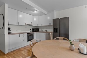Una cocina moderna con armarios blancos, electrodomésticos de acero inoxidable y una mesa de comedor de madera.
