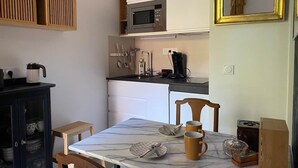 Eine kleine Küche mit Mikrowelle, Kaffeemaschine und einem Esstisch mit Stühlen.