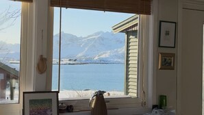 Una cocina con vista a un lago y montañas, con armarios de madera, una mesa y una silla.