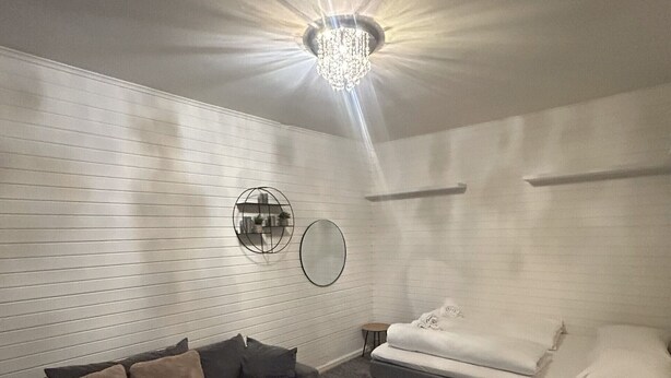 Un salon moderne avec un canapé d’angle gris, une petite table ronde et un canapé blanc avec un lit blanc.