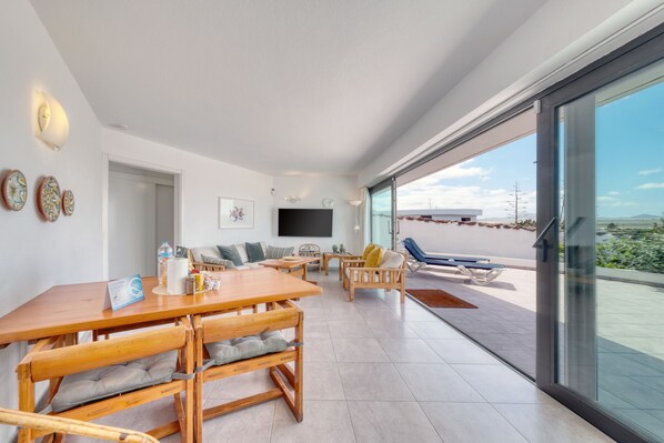 Un espacio habitable moderno con comedor, asientos, televisor de pantalla plana y balcón con vistas.
