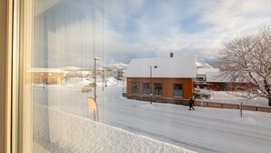 A snowy street with buildings, a clear sky, and a person walking. - Lofoten Premium Suites #Aurora (Vestvågøy)