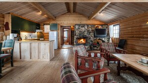 L’intérieur d’une cabane en rondins comprend une cuisine, un coin repas, une cheminée et un espace détente.