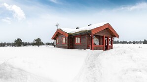 Une cabane en bois avec un toit rouge et un sol recouvert de neige.