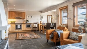 Une cuisine moderne avec des meubles en bois, un coin repas avec une table et des chaises, et un salon avec un canapé et un tapis.