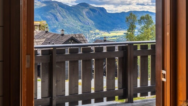 Un balcon en bois offrant une vue sur les montagnes et un ciel nuageux.