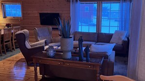 A wooden interior with a sofa, armchairs, a coffee table, and a TV. - Pollstua, cosy cabin with amazing views (Vestvågøy)