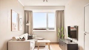 Ein modernes Wohnzimmer mit Sofa, Couchtisch, Fernseher und einem Fenster mit Blick.